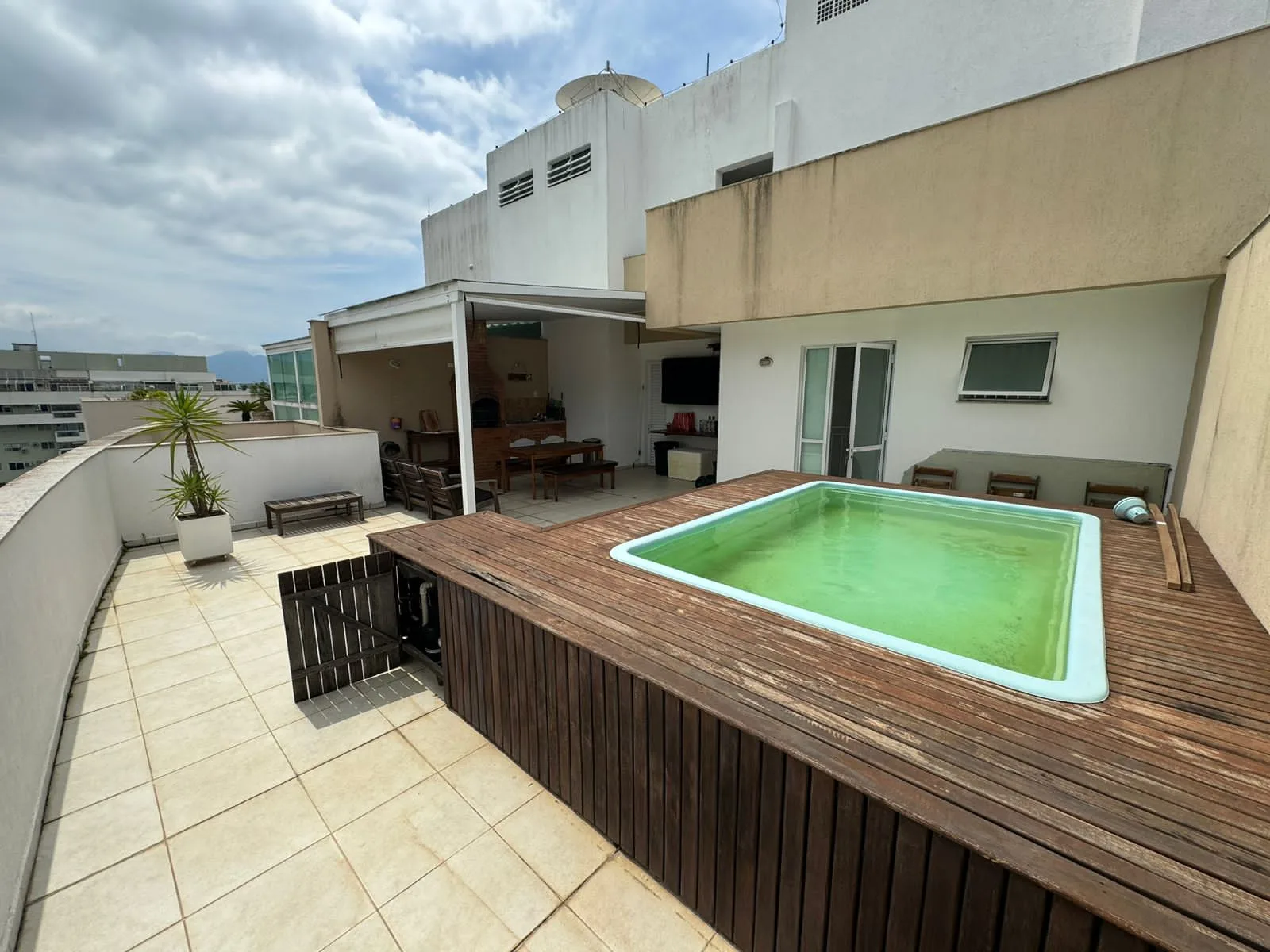 Terraço da cobertura com piscina privativa em deck de madeira e área gourmet coberta