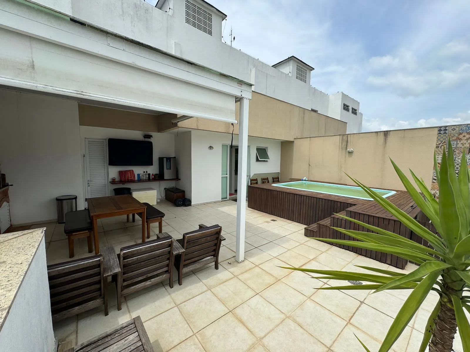 Área gourmet do terraço com churrasqueira, mesa, TV e piscina privativa