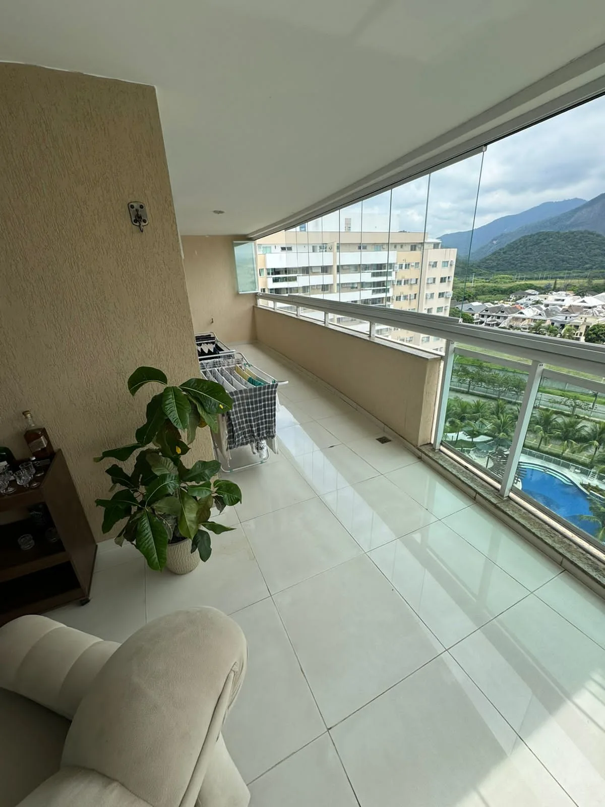 Varanda envidraçada com vista para a piscina do condomínio e montanhas