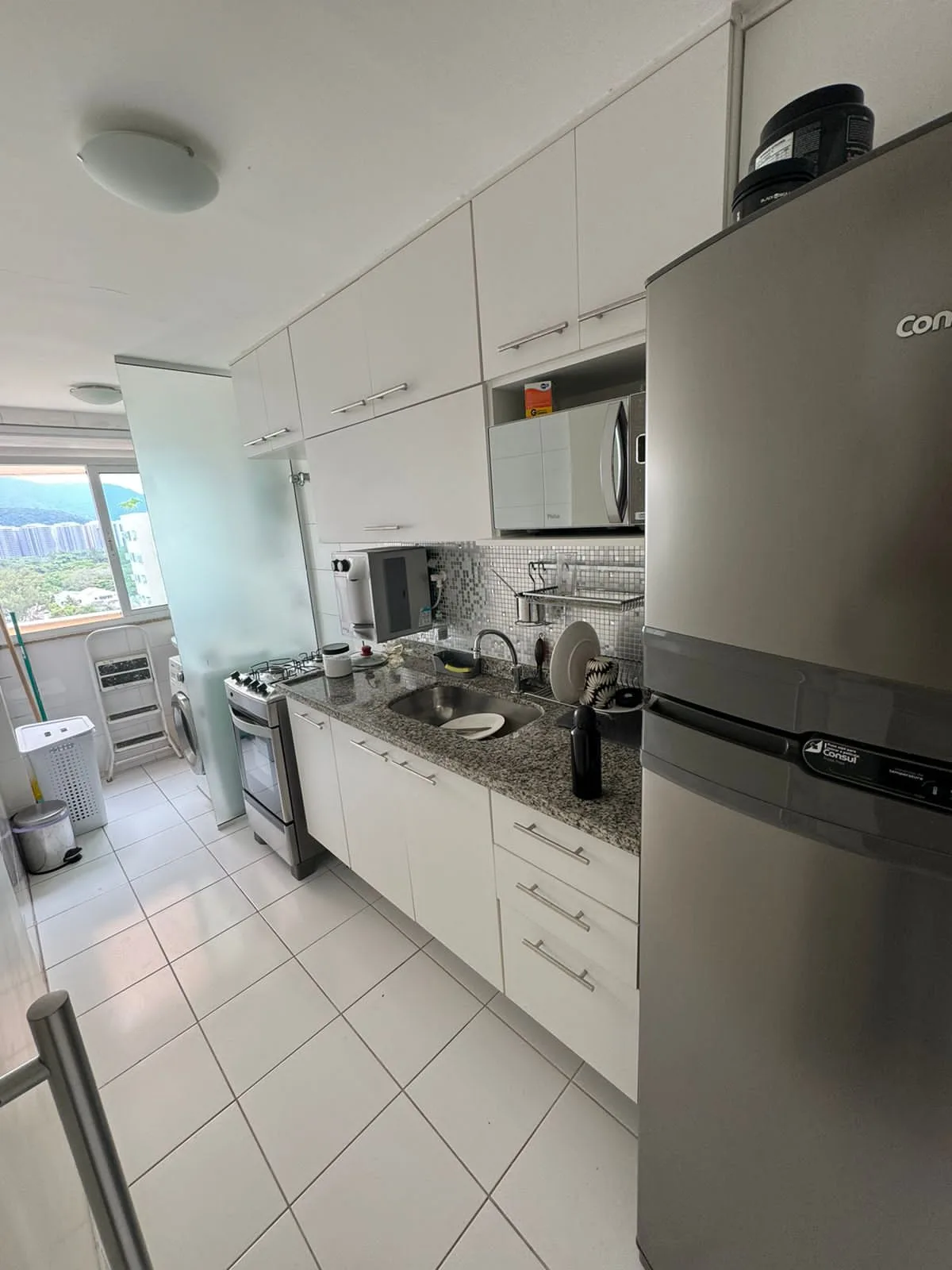 Cozinha planejada com eletrodomésticos e área de serviço integrada