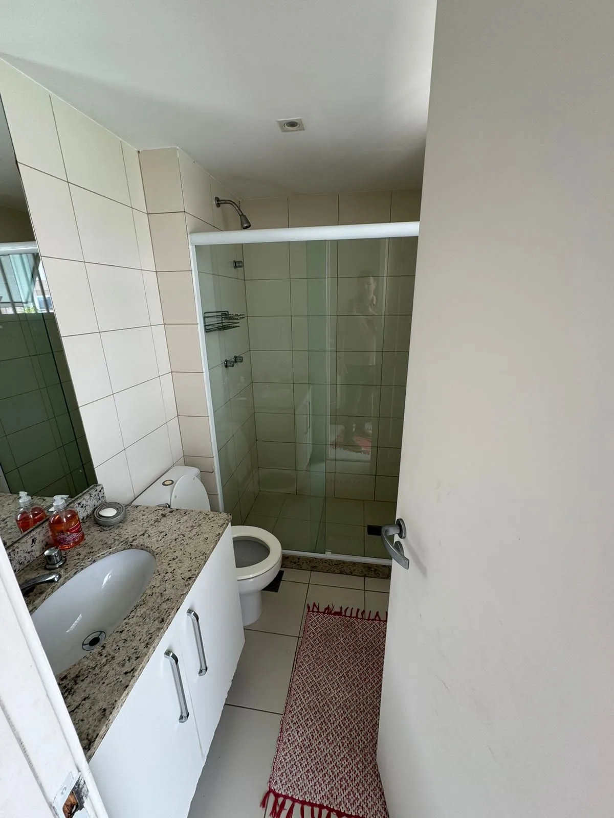 Banheiro com bancada em granito e box de vidro