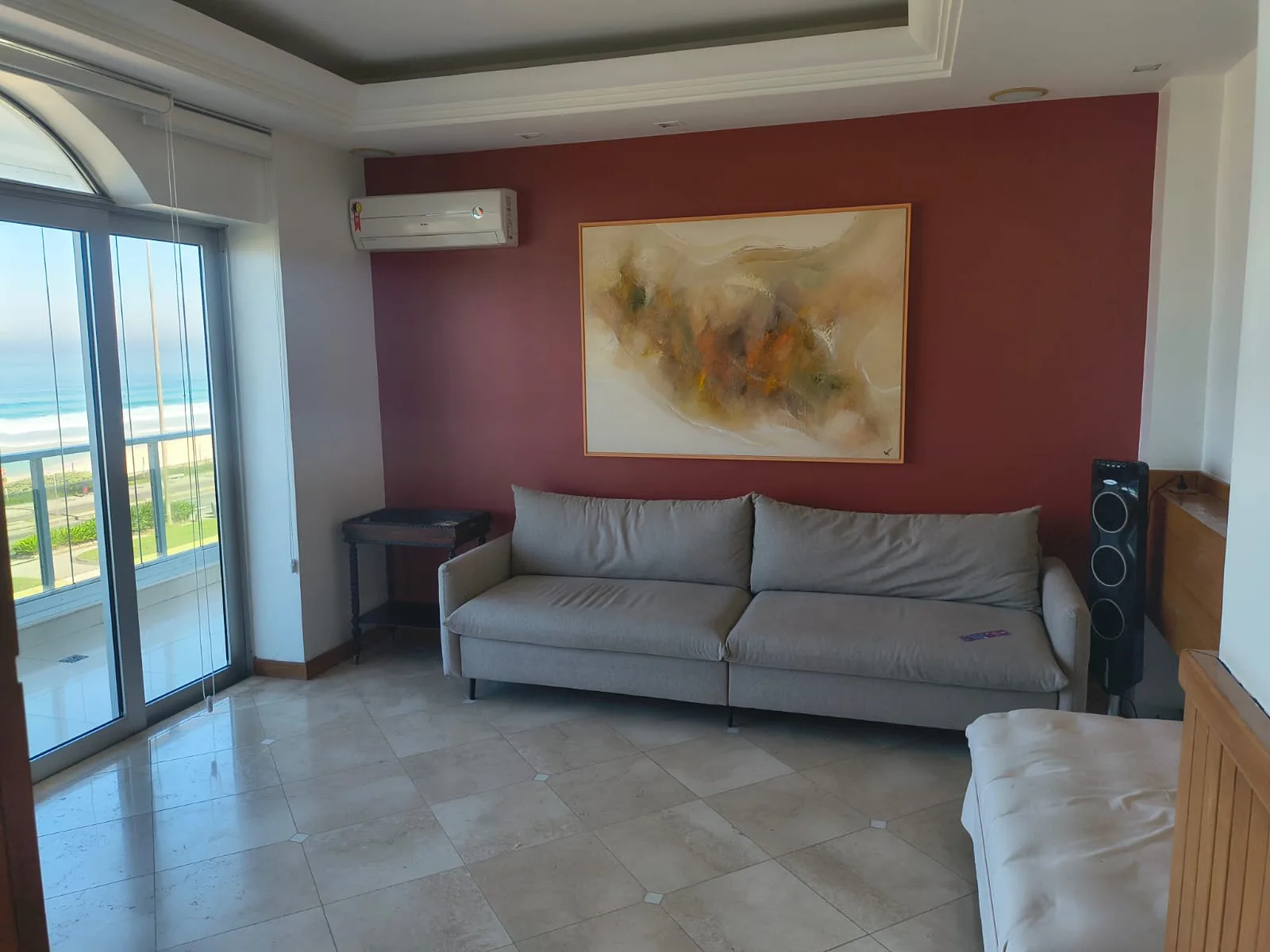 Sala íntima com sofá e vista lateral para o mar