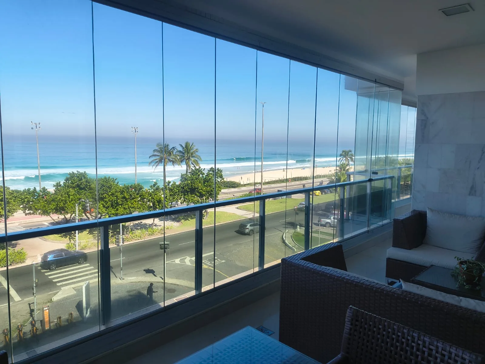 Varanda em cortina de vidro com vista frontal para a praia da Barra