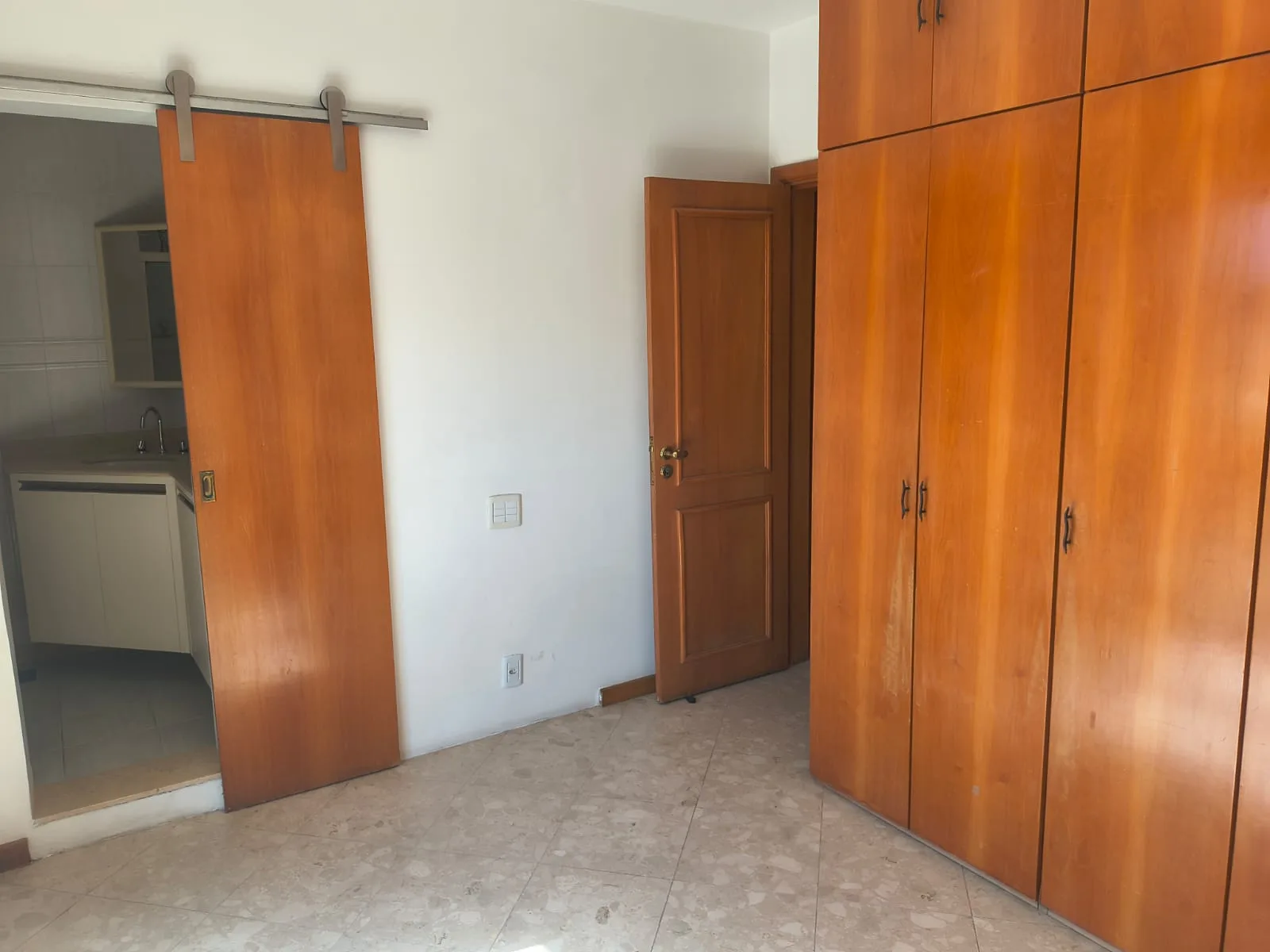 Suíte com closet planejado e porta de correr em madeira
