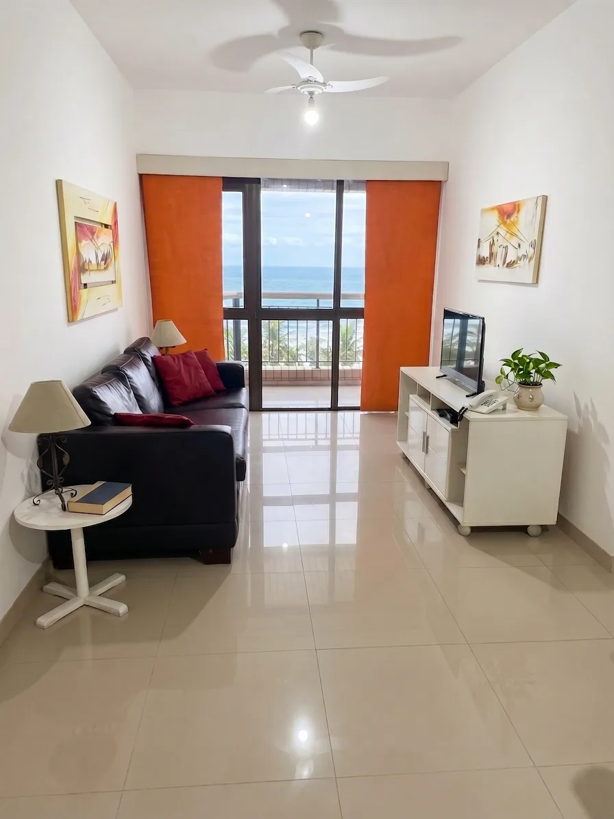 Living com sofá de couro, TV e cortina laranja com vista para o mar