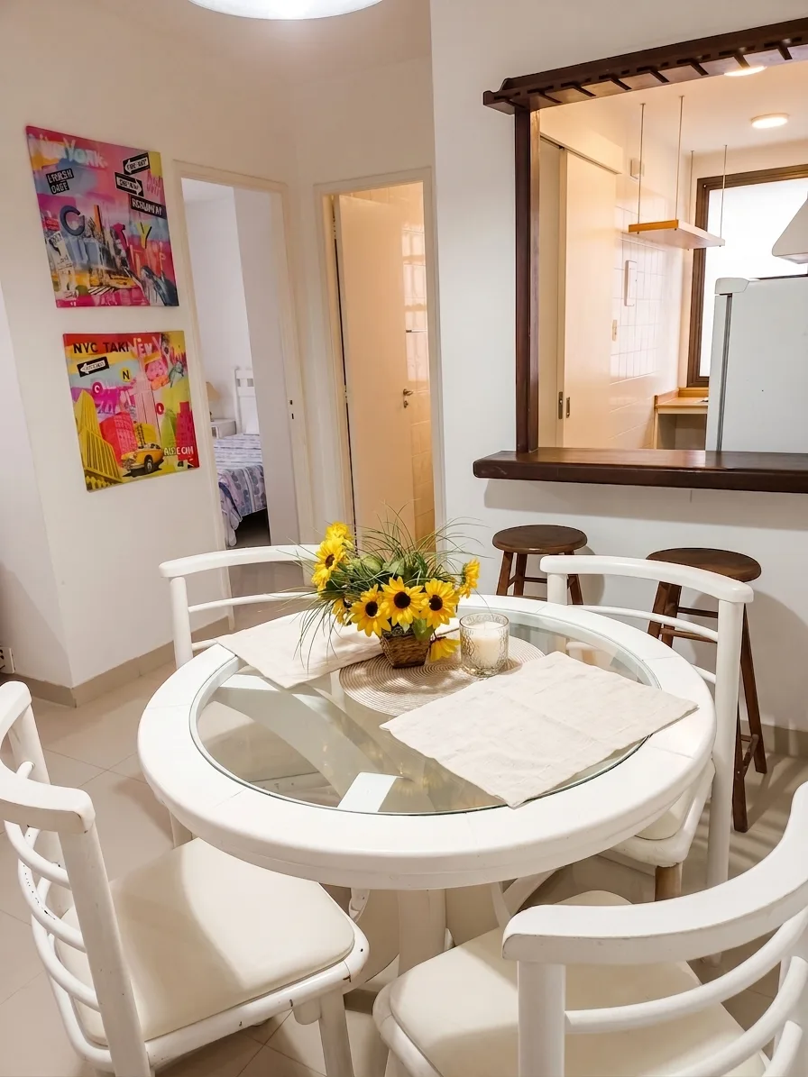 Sala de jantar com mesa redonda de vidro e passa-pratos para a cozinha