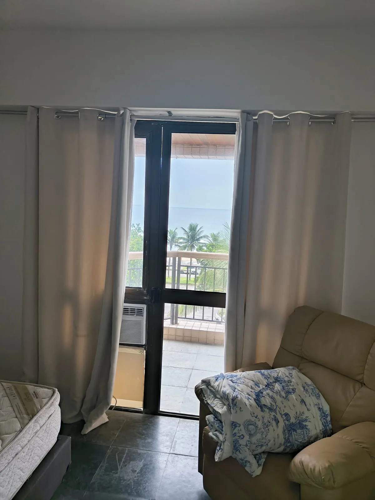 Sala com acesso à varanda e vista mar entre coqueiros