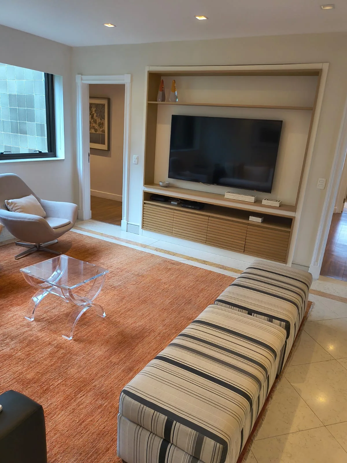 Sala de TV com painel em madeira e poltrona