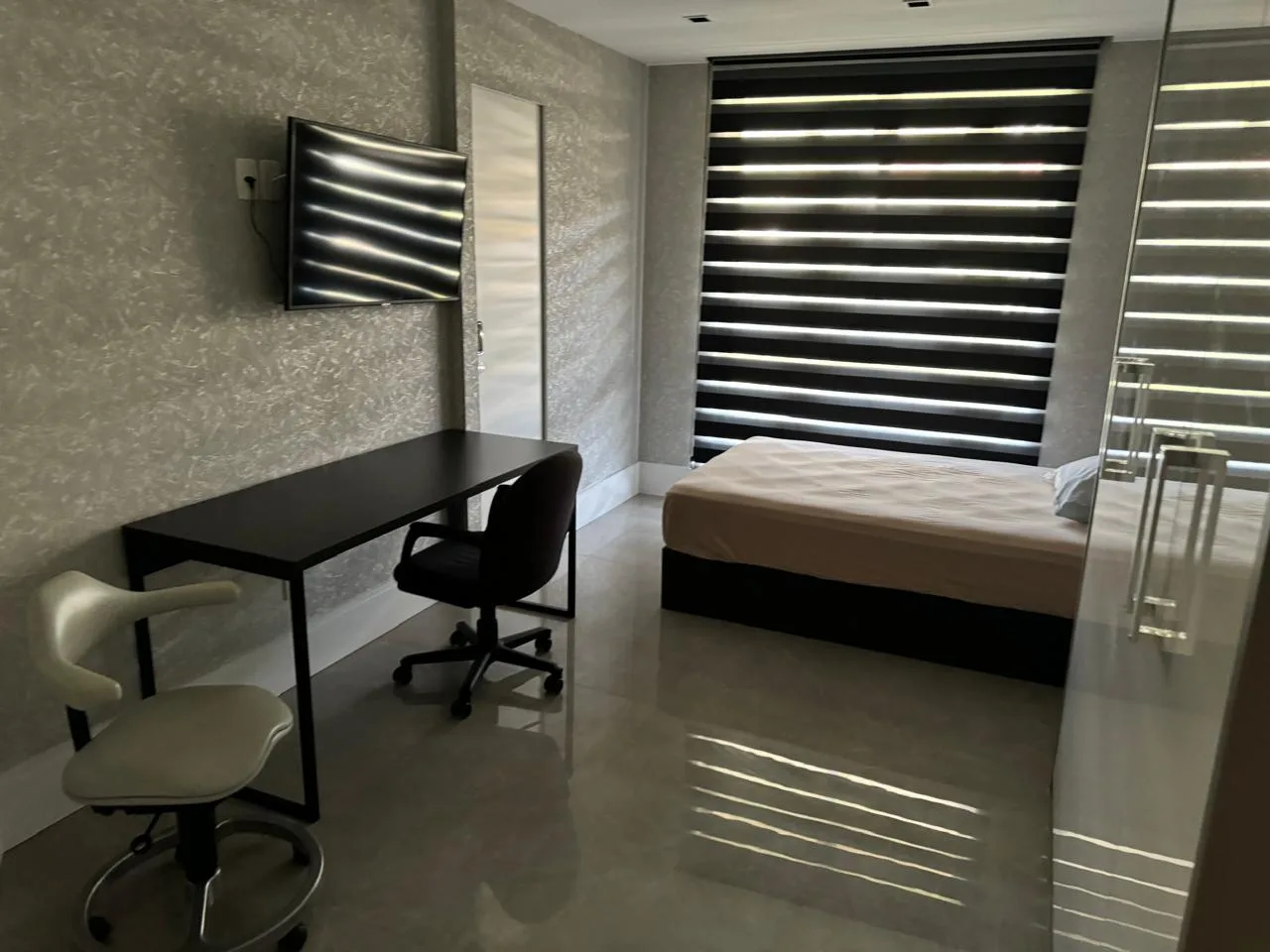 Suíte com acabamento moderno e persiana zebra