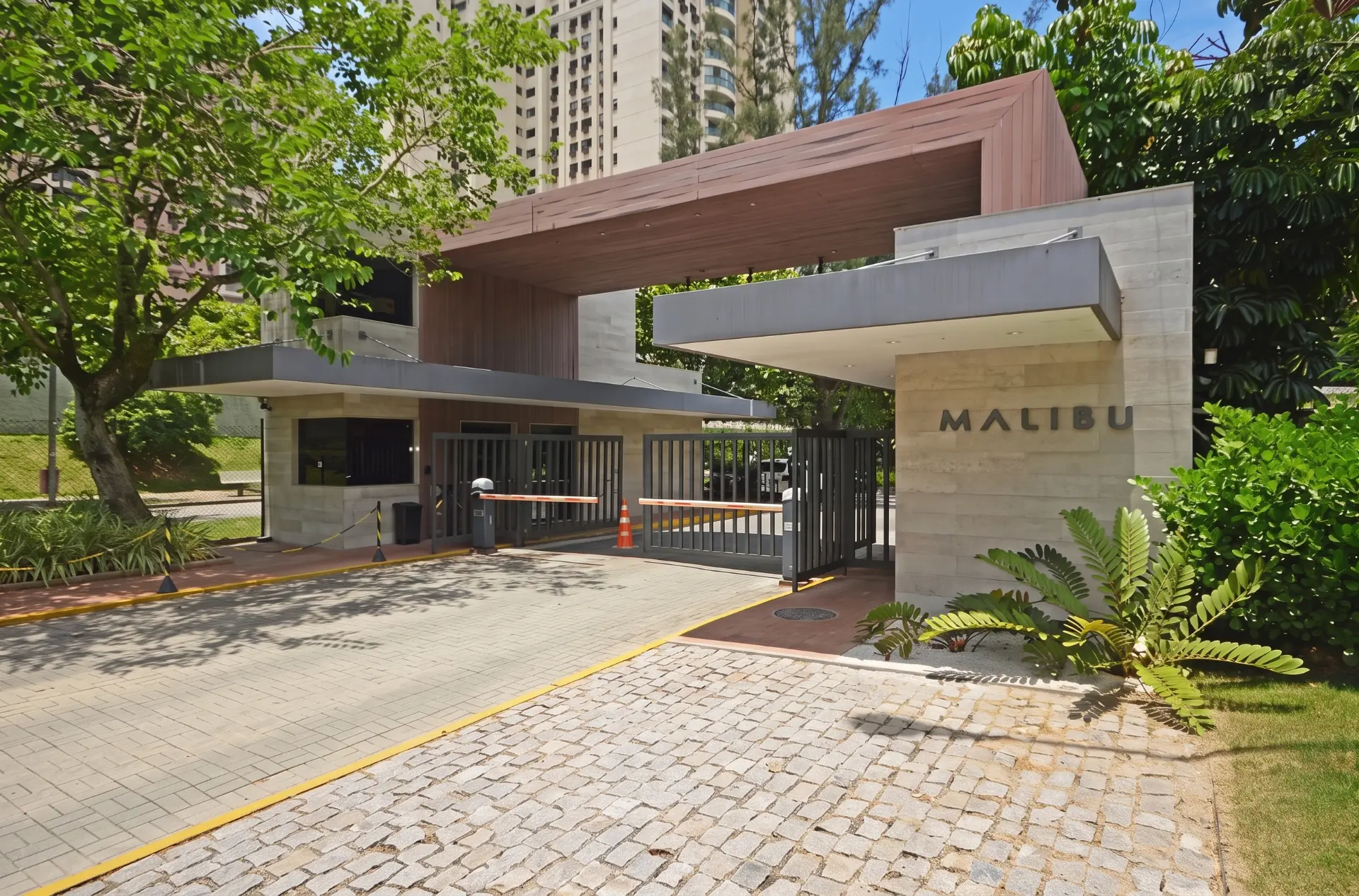 Fachada da guarita do Condomínio Malibu em pedra e madeira na Av. das Américas