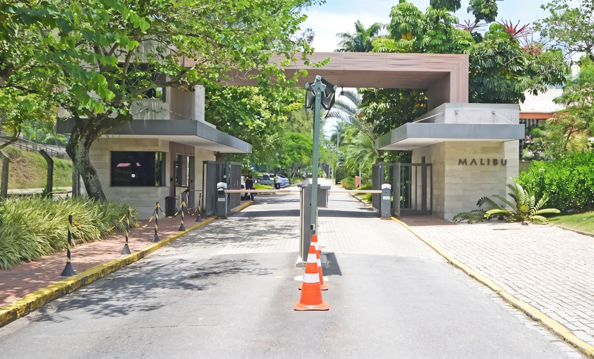 Entrada principal do Condomínio Malibu na Avenida das Américas, Barra da Tijuca — portaria e rua interna arborizada
