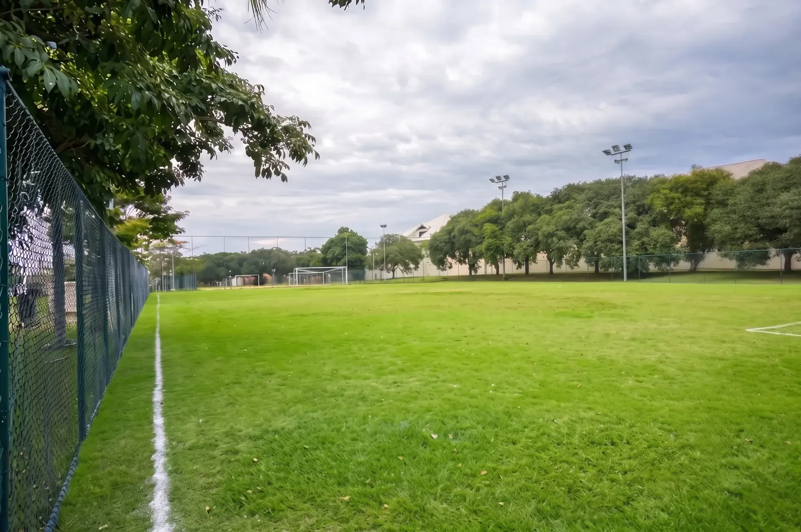 Campo de futebol com gramado natural e iluminação no Condomínio Mansões