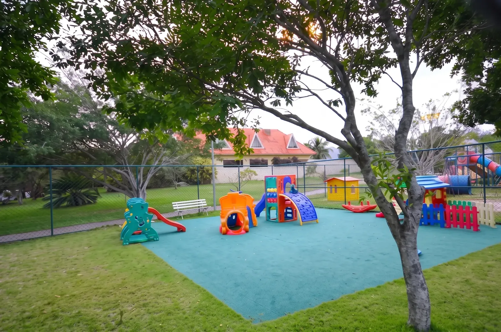 Playground infantil com piso emborrachado e áreas verdes no Condomínio Mansões