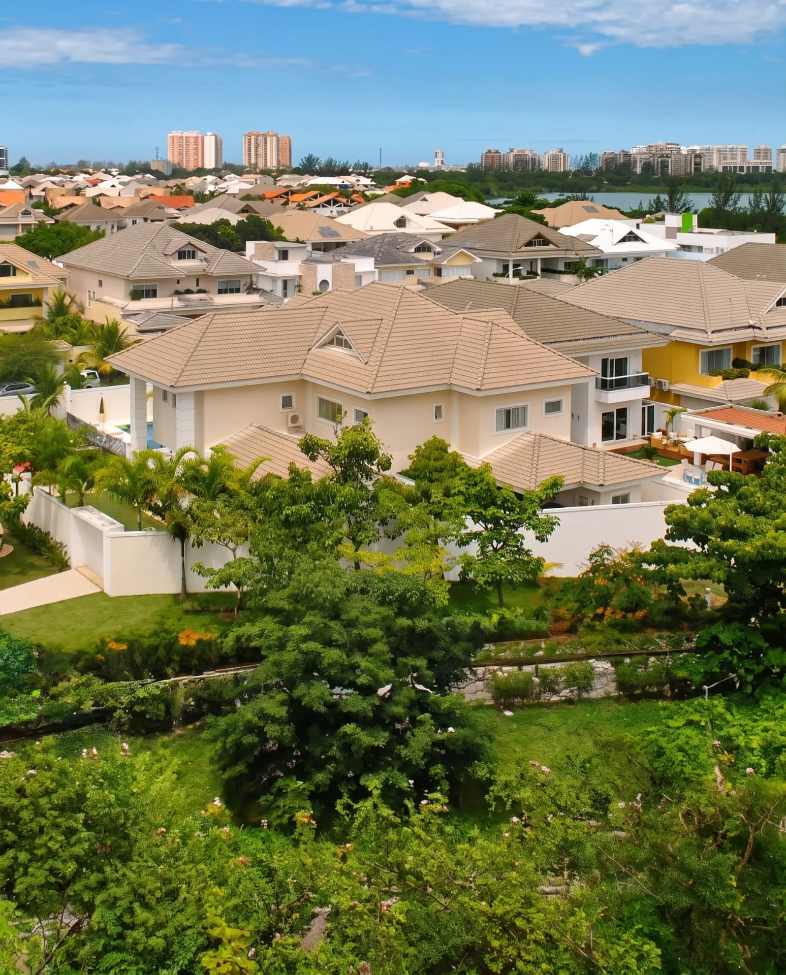 Vista aérea das casas do Condomínio Quintas do Rio com a Lagoa e o skyline da Barra da Tijuca ao fundo