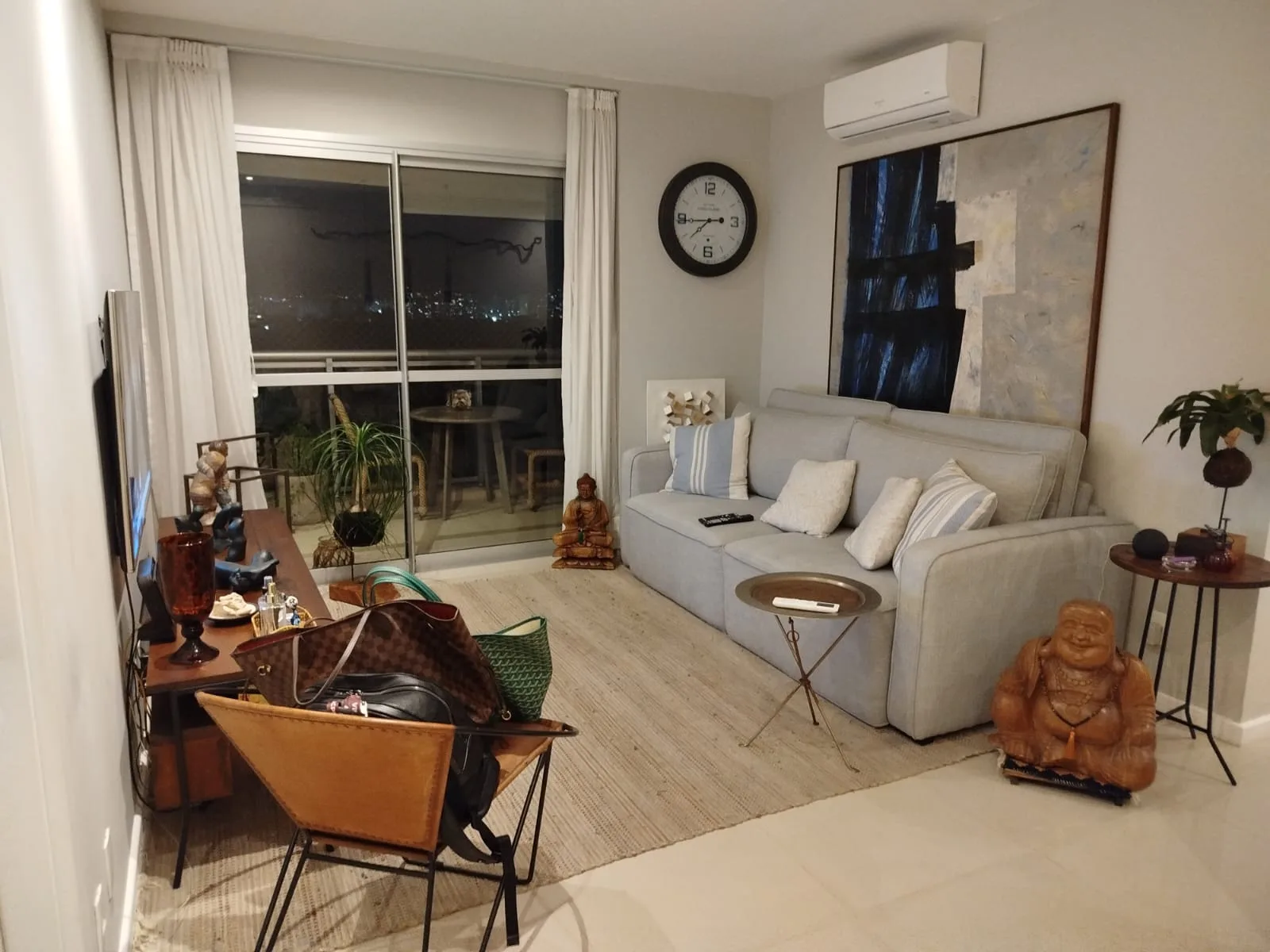 Sala de TV com sofá cinza e vista para varanda