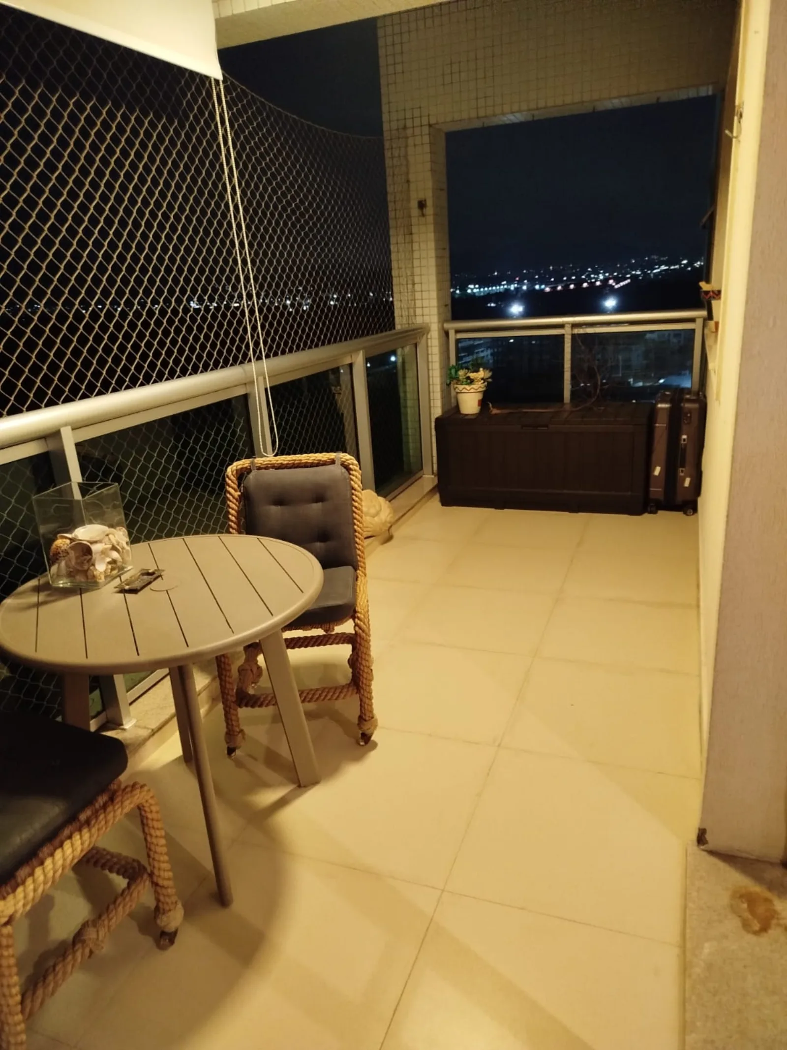 Varanda iluminada à noite com vista panorâmica da Barra Olímpica